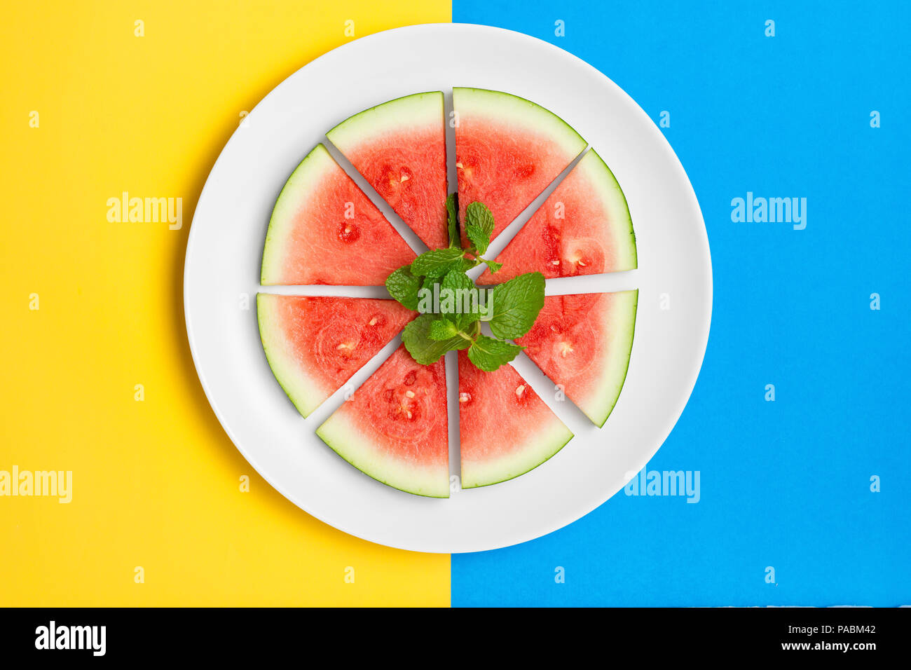 Sliced watermelon on a plate with fresh mint leaves. Flat lay image Stock Photo