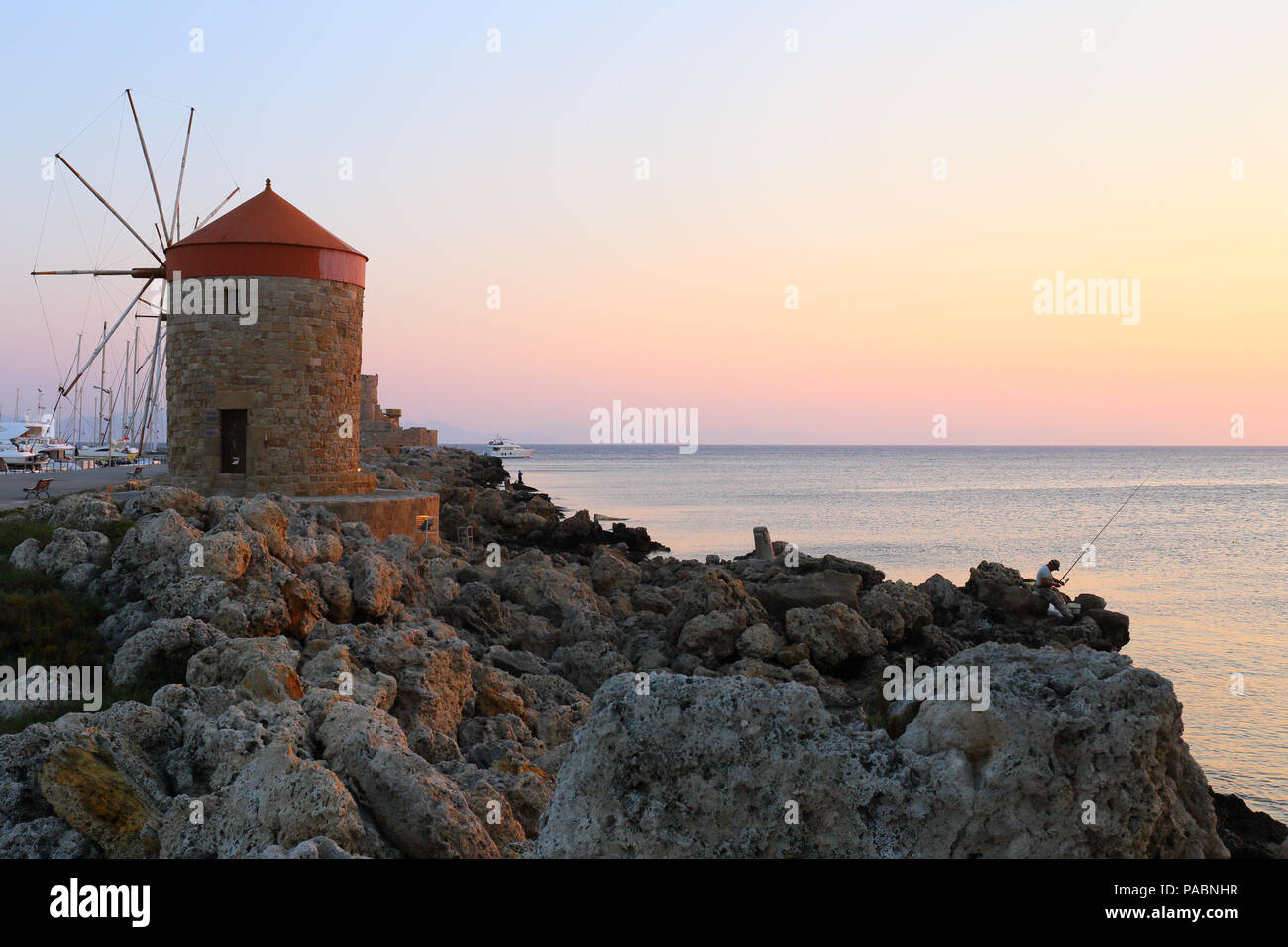 The medieval windmills in Mandraki harbour in Rhodes, Greece at sunrise. Stock Photo