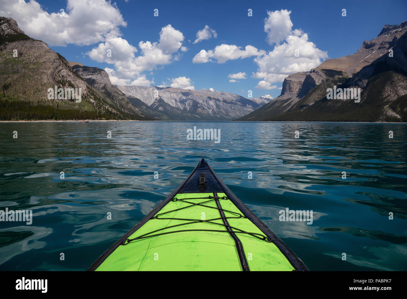 Kayaking in Lake Minnewanka during a vibrant sunny summer day. Taken in