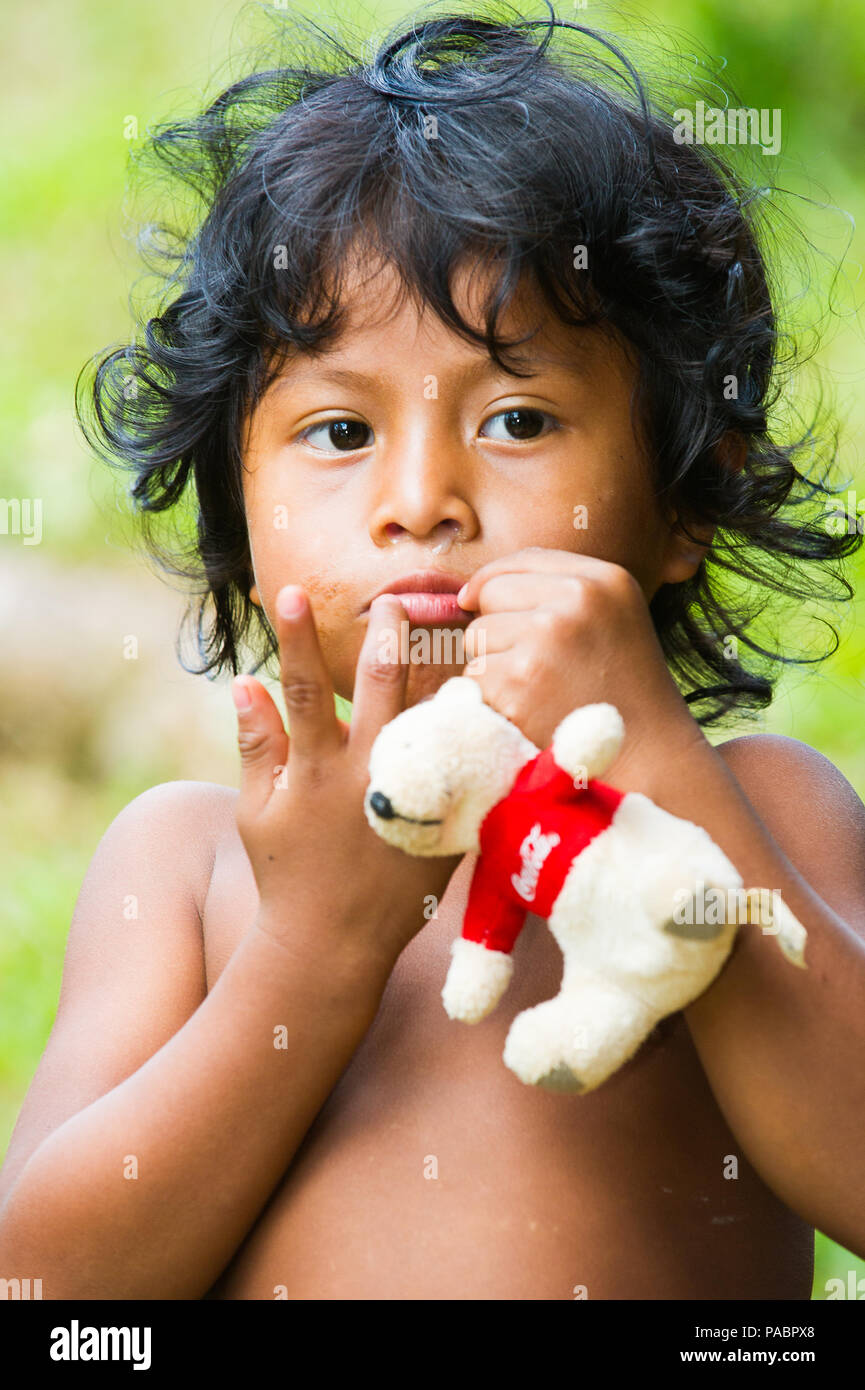 EMBERA VILLAGE, PANAMA, JANUARY 9, 2012: Unidentified native Indian girl plays with a Teddy bear in a cabin in Panama, Jan 9, 2012. Indian reservation Stock Photo