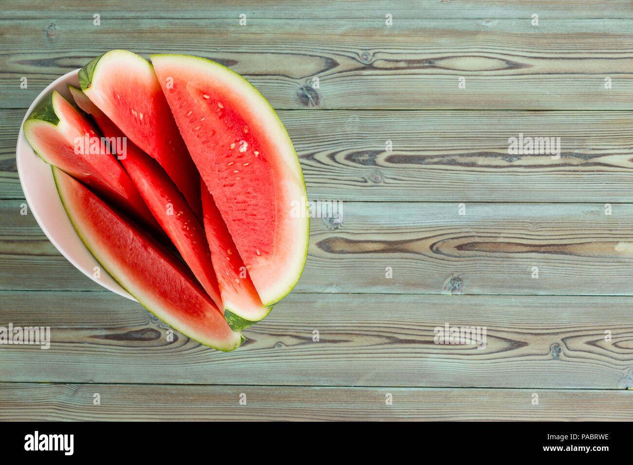Wedges of delicious juicy fresh ripe watermelon for a healthy summer snack served on a plate on an old wood picnic table viewed from overhead with cop Stock Photo