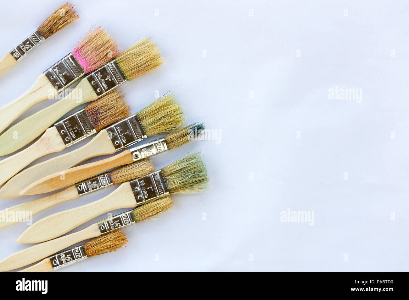 Used paint brushes against white paper with copy space ready for artwork Stock Photo