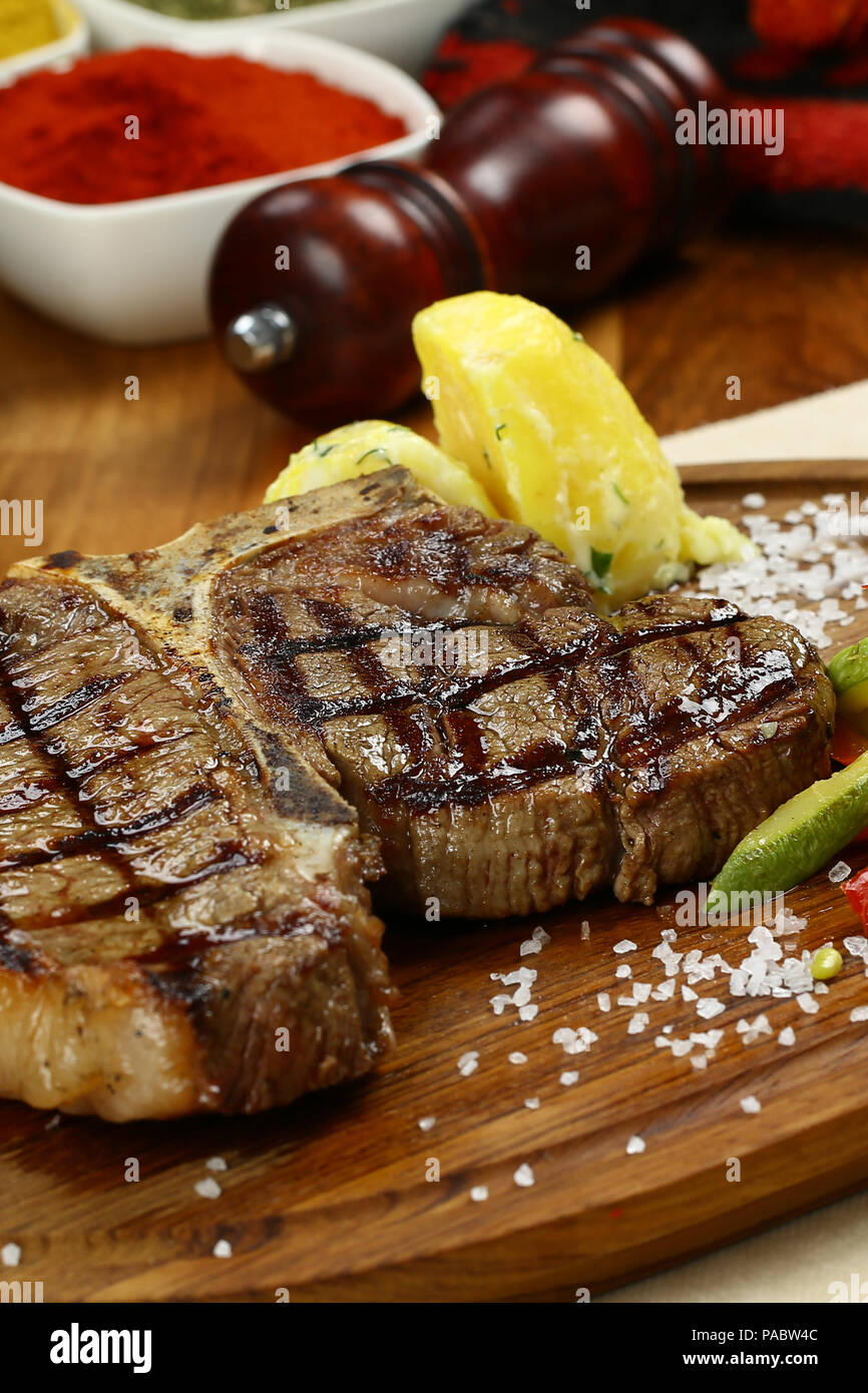 Roasted BBQ TBone Steak and herb butter on wooden cutting board Stock