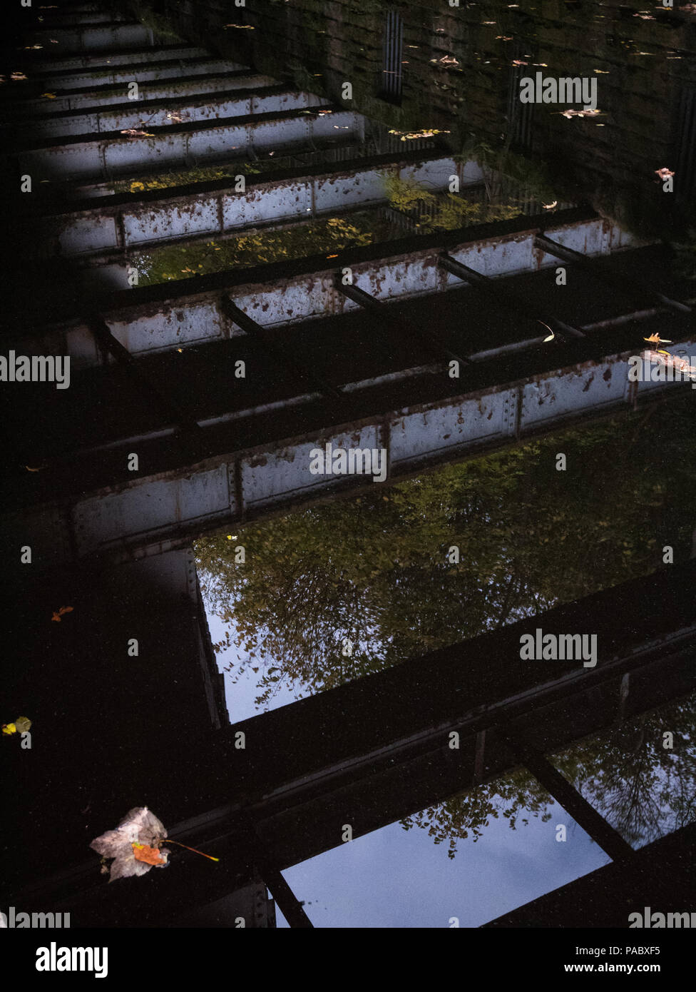 An iron bridge reflected in the Leeds Liverpool canal near Saltaire, United Kingdom. Stock Photo