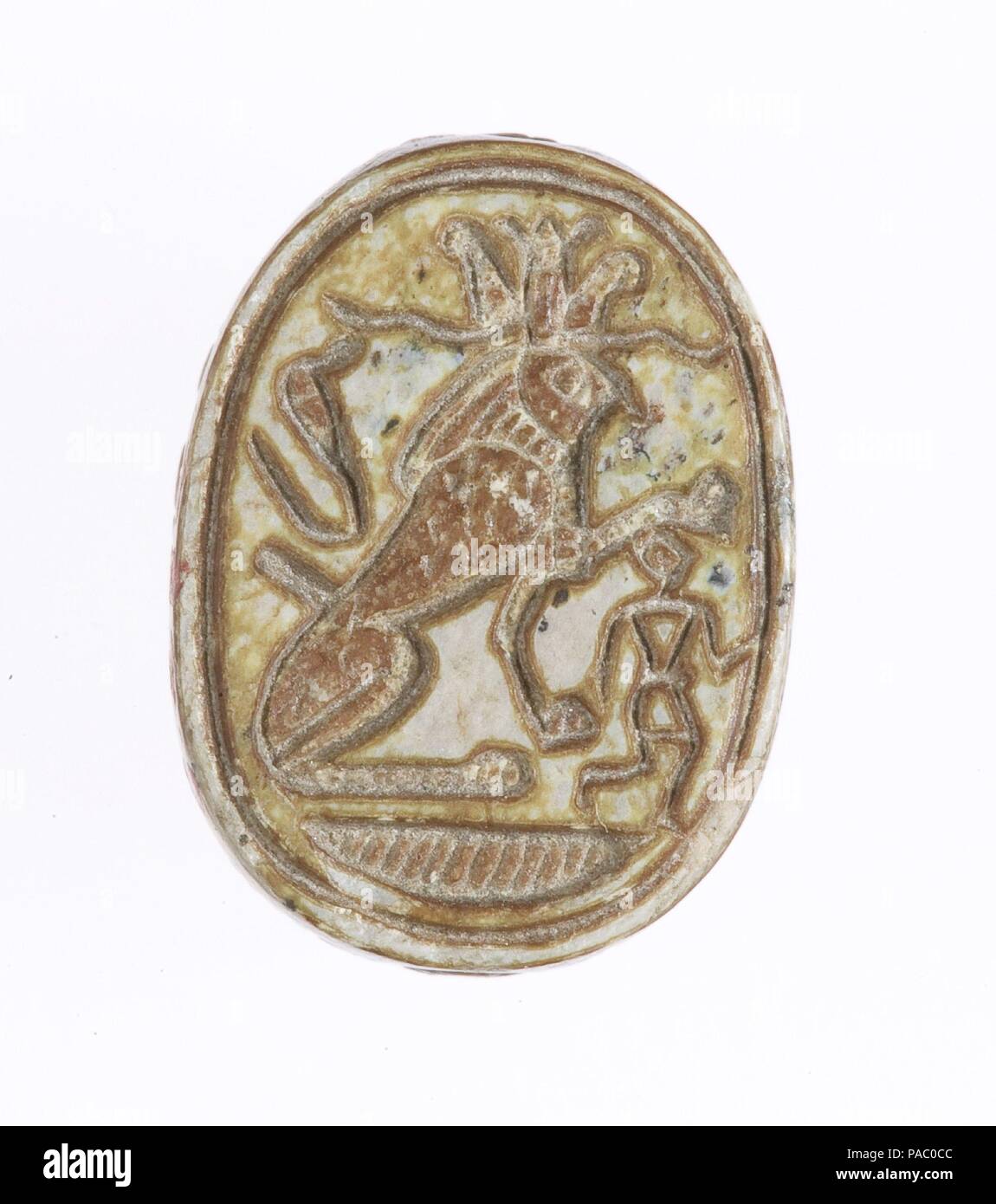 Scarab Inscribed With a Protective Motif. Dimensions: L. 1.5 cm (9/16 in); w. 1.2 cm (1/2 in); th. 0.8 cm (5/16 in). Dynasty: Dynasty 18, early. Reign: reign of Ahmose-Joint reign. Date: ca. 1550-1458 B.C..  The scarab's base depicts a falcon-headed sphinx wearing the "atef" crown while subduing an enemy of Egypt. The falcon represents Re-Herakhti - the god Horus when he is merged with the sun. Museum: Metropolitan Museum of Art, New York, USA. Stock Photo