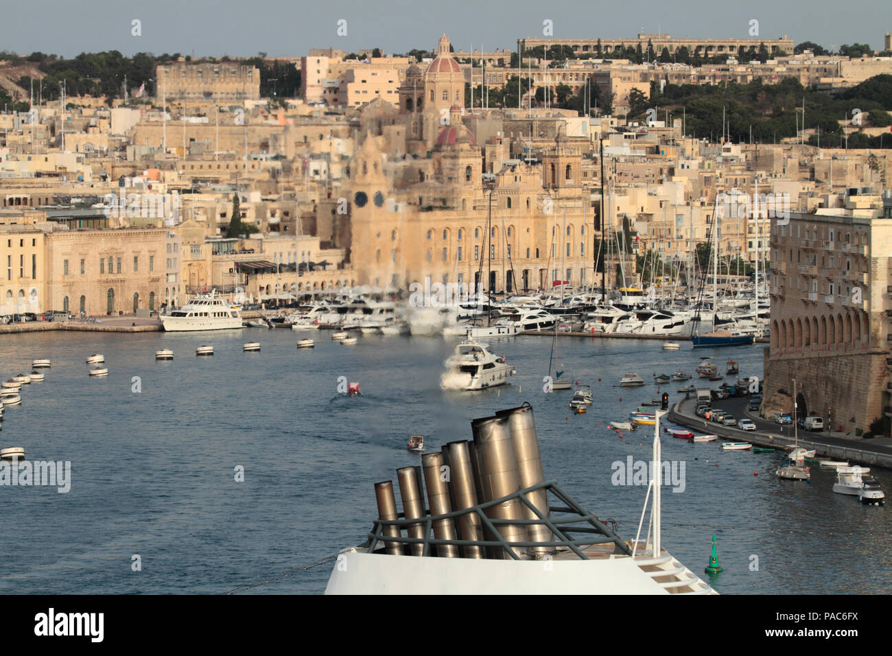 Clean exhaust from the smokestack of a cruise ship visible against the background of Birgu in Malta. Carbon emissions from ships and global warming. Stock Photo
