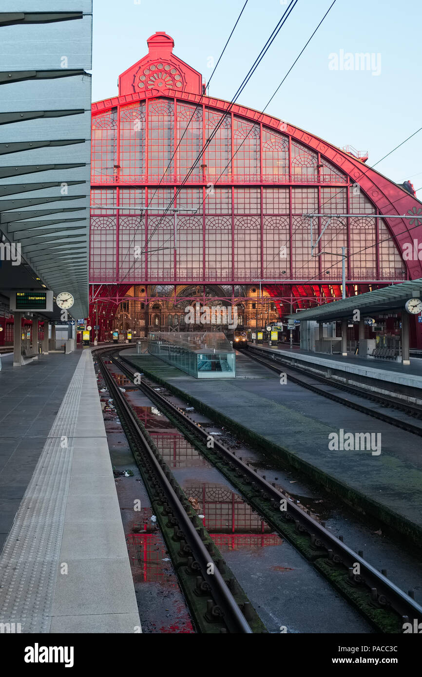 Antwerp Central train station pictured after a rainy day. The monumental red iron building structure is reflected in a puddle Stock Photo