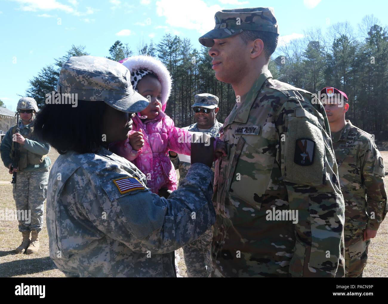 U.S. Army Spc. Kerene Nobles, pins on the rank on her husband, Sgt. Samuel Nobles, both assigned to 55th Signal Company (Combat Camera), at Fort George G. Meade, Md., March 2, 2016. The promotion from specialist to sergeant marks the responsibility instilled into the new noncommissioned officer. (U.S. Army photo by Spc. Alyssa Madero/Released) Stock Photo