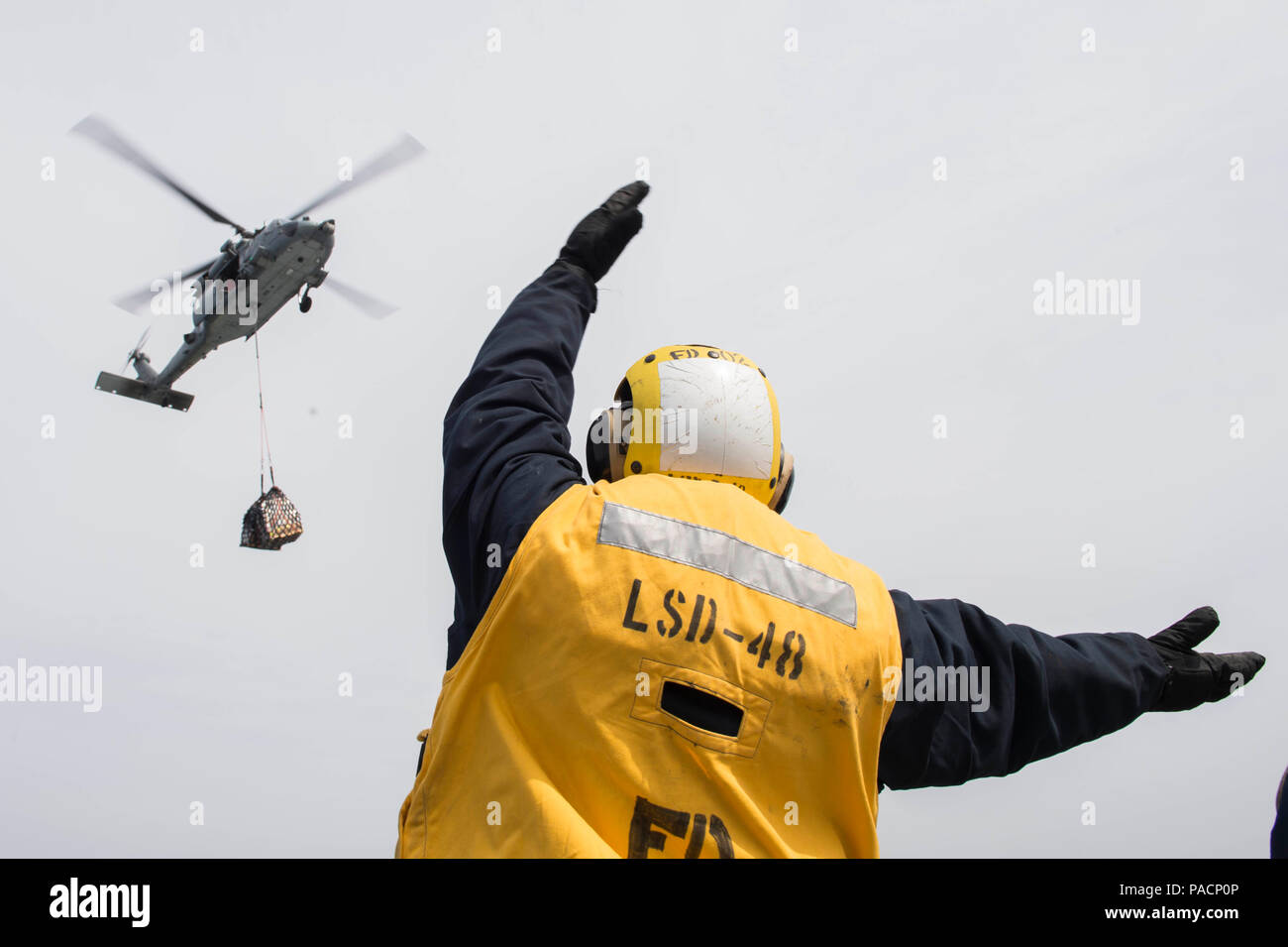 160316-N-RM689-133 EAST SEA (March 16, 2016) - A Sailor assigned to amphibious dock landing ship USS Ashland (LSD 48) directs the pilot to help get the pallet down onto the flight deck during a vertical replenishment (VERTREP) at sea. Ashland is assigned to the Bonhomme Richard Expeditionary Strike Group and is participating in Ssang Yong 16, a biennial combined amphibious exercise conducted by forward-deployed U.S. forces with the Republic of Korea navy and Marine Corps, Australian army and Royal New Zealand army forces in order to strengthen our interoperability and working relationships acr Stock Photo