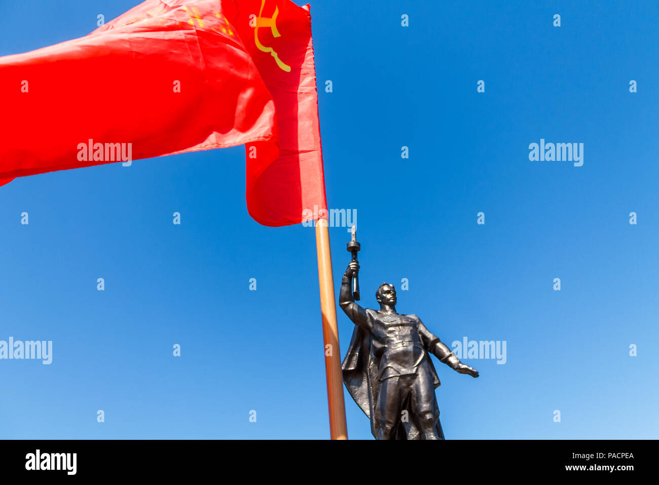 Monument to a Soviet soldier with a submachine gun in the hand of a participant in the Second World War with red flag USSR. Stock Photo