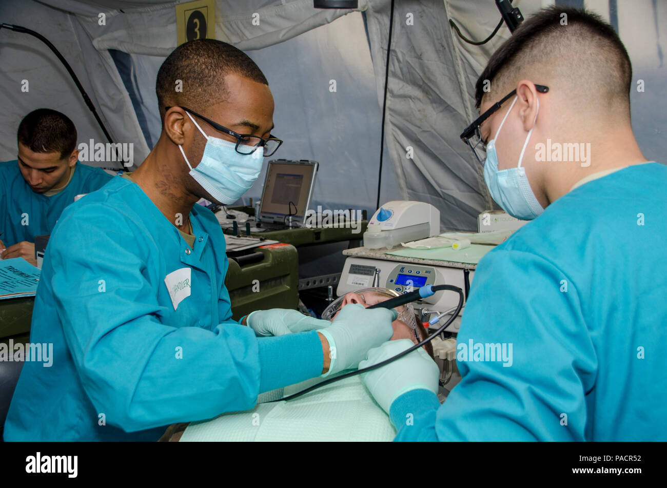 Spc. Ricardo Chandler (left), a dental hygienist with 673rd Dental Company (Area Support), 62nd Medical Brigade, performs dental work on a Soldier as Pfc. Kyle Ayala, also a dental assistant with 673rd DC(AS), helps at Joint Base Lewis-McChord, Wash., March 9, 2016. This was part of the Dental Access Regulars Treatment Event held March 8-17, 2016. (U.S. Army photo by Staff Sgt. Samuel Northrup, 1-2 SBCT Public Affairs) Stock Photo