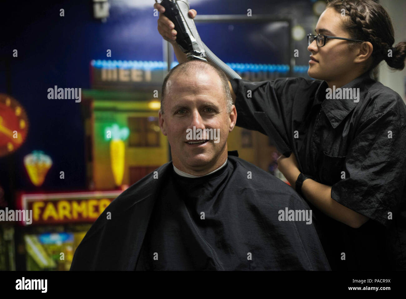 Wash. (July 19, 2017) Ship's Serviceman Seaman Stephanie Santana, from Hialeah, Fla., gives Capt. Scott Miller, executive officer of the aircraft carrier USS John C. Stennis (CVN 74), the first hair cut in the ship’s newly remodeled barber shop since the beginning of the ship’s planned incremental availability (PIA). Services such as the barber shop, coffee shop, ship’s store and galleys are returning for crew use for the first time since closing at the beginning of PIA. John C. Stennis is conducting a PIA at Puget Sound Naval Shipyard and Intermediate Maintenance Facility, during which the sh Stock Photo