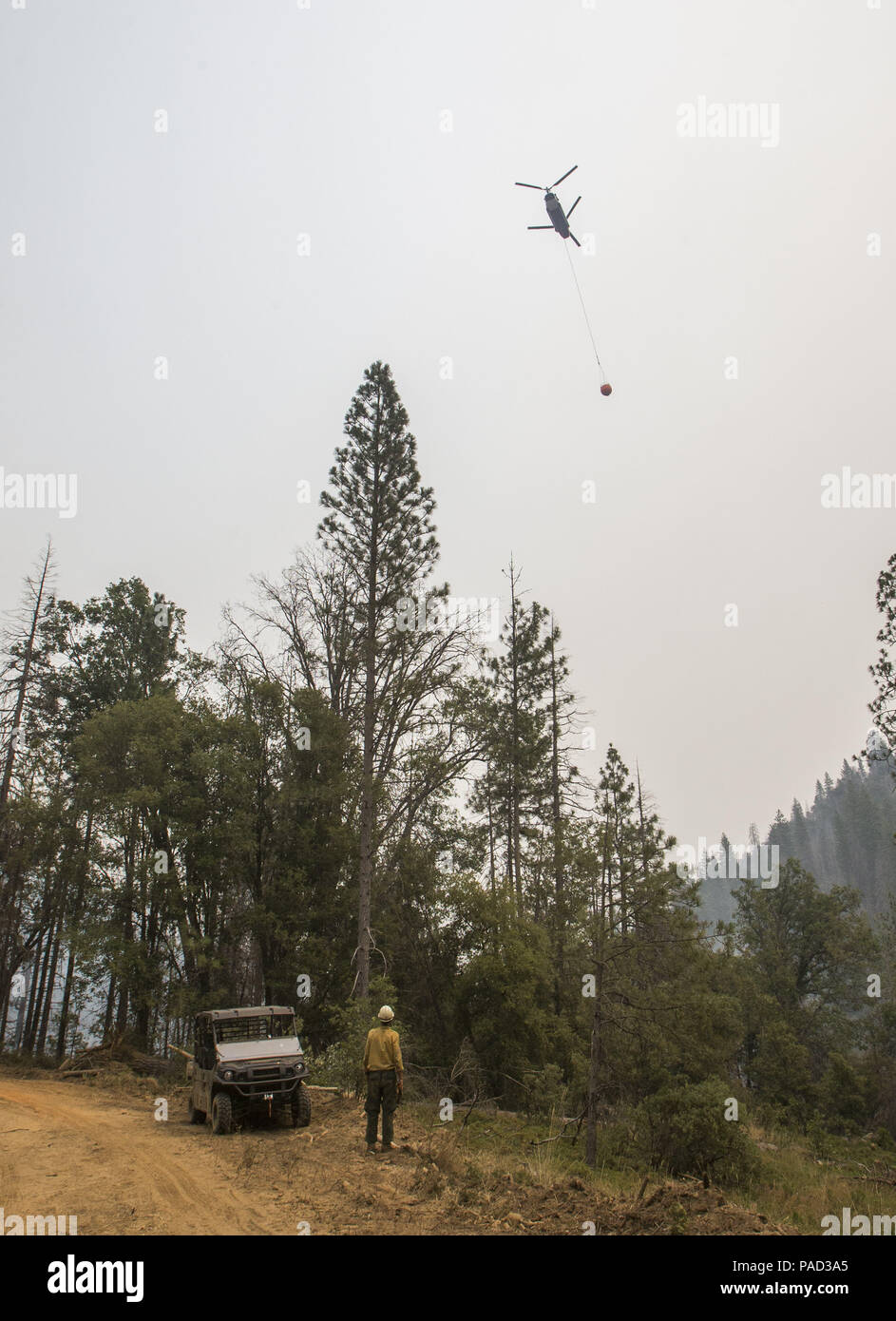 Mariposa, California, U.S.A. 21st July, 2018. A US Forest Service Firefighter watches as a helicopter drops water on a fire that was running up the Skelton Creek drainage. The Ferguson Fire in Mariposa County just west of Yosemite National Park has burned over 29,000 acres and is 6% contained as of Saturday July 21, 2018 according to U.S. Forest Service. Credit: Marty Bicek/ZUMA Wire/Alamy Live News Stock Photo