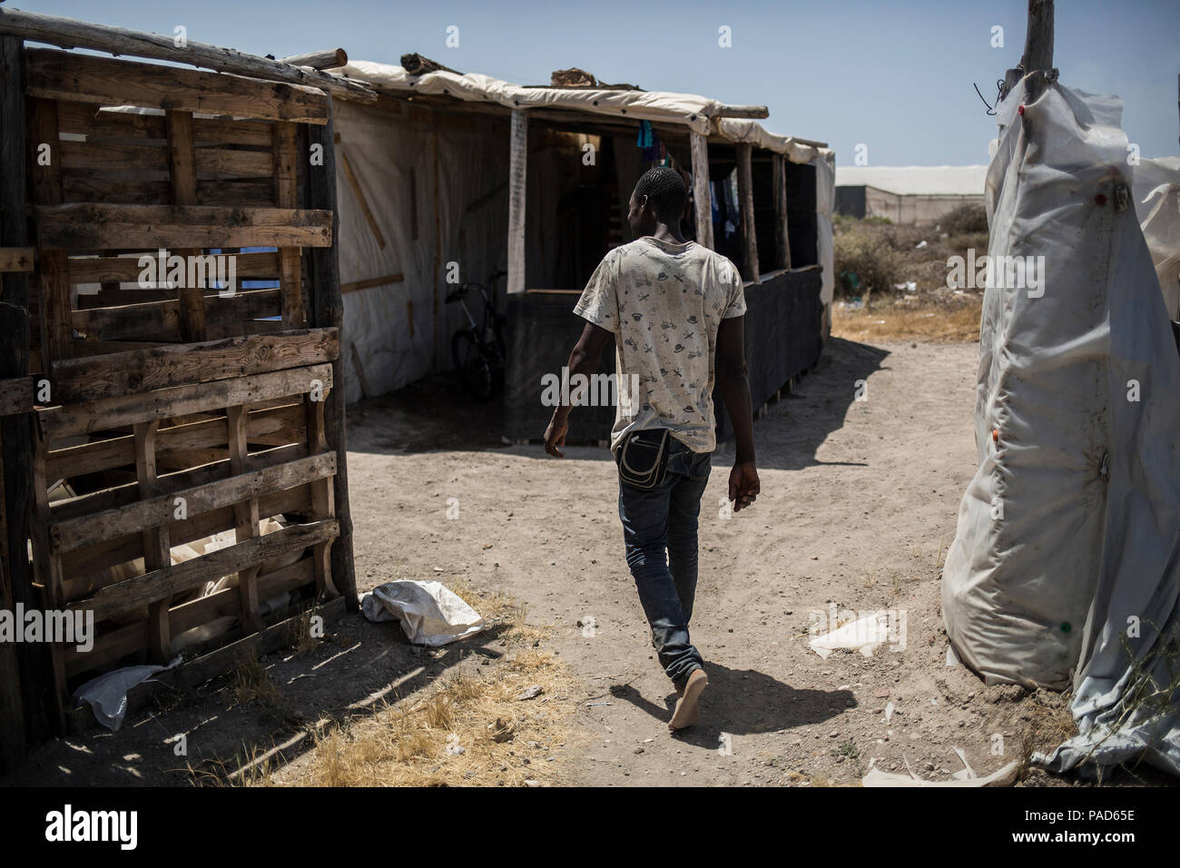 Nijar, Spain. 21st July, 2018. 21.07.2018, Spain, Almería, Nijar: A migrant walks to his hut in a permanet settlement near Nijar, Almeria, Spain; Over 50 african undocumented migrants live in poor conditions while hoping to get some work on the nearby plantations. Credit: Javier Fergo/dpa/Alamy Live News Stock Photo