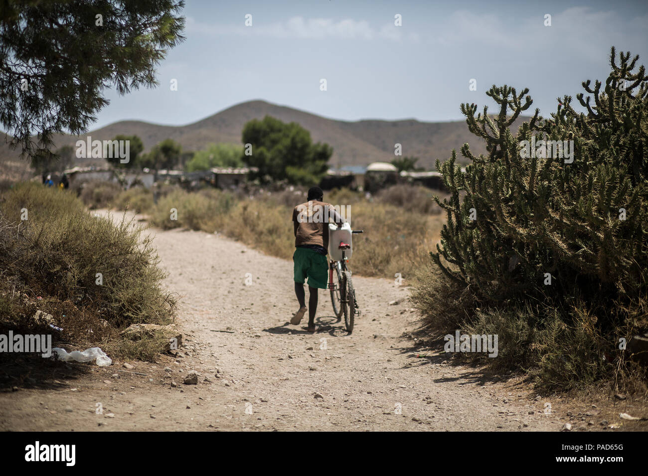 Nijar, Spain. 21st July, 2018. 21.07.2018, Spain, Almería, Nijar: A migrant carries a water tank to his hut in a permanet settlement near Nijar, Almeria, Spain; Over 50 african undocumented migrants live in poor conditions while hoping to get some work on the nearby plantations. Credit: Javier Fergo/dpa/Alamy Live News Stock Photo