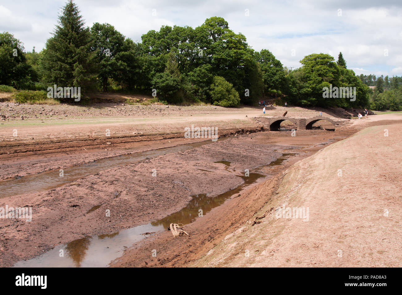 Llwyn Onn reservoir, Merthyr Tydfil, South Wales,  UK.  22 July 2018.  UK weather: The heatwave has caused this reservoir to become severely depleted, with the water line well below normal.  A stream that runs into the reservoir has dried up.  Pont Yr Daf bridge, an old bridge in use before the reservoir's construction, now usually underwater, has been uncovered.  Credit: Andrew Bartlett/Alamy Live News Stock Photo