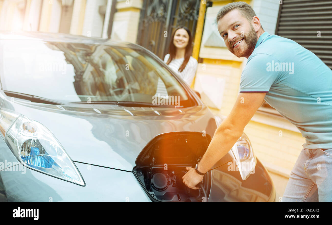 Young cute couple charging an electric car while travelling Stock Photo