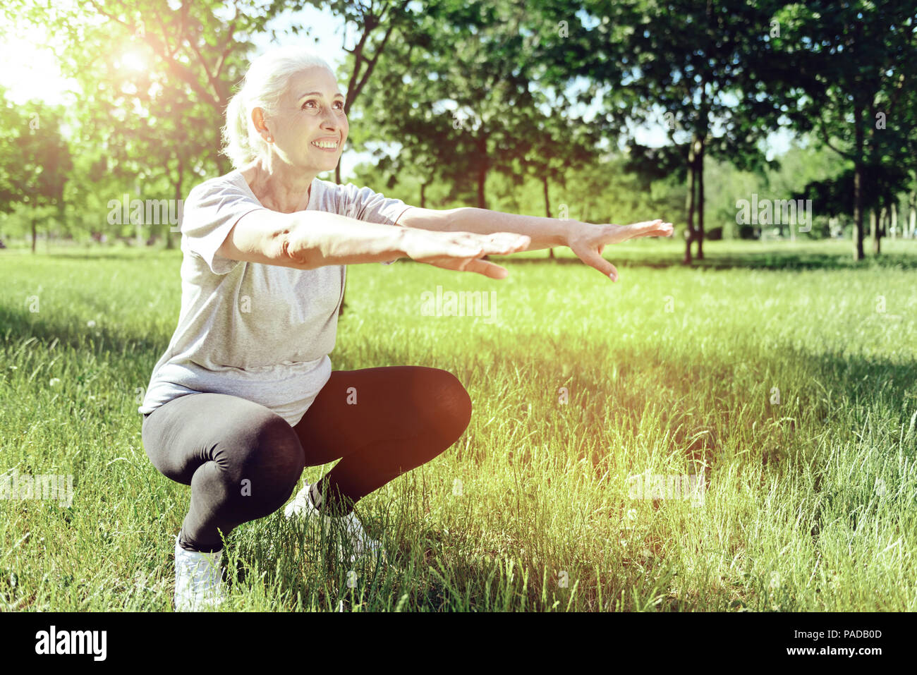 Elderly woman bending her knees in a park Stock Photo Alamy