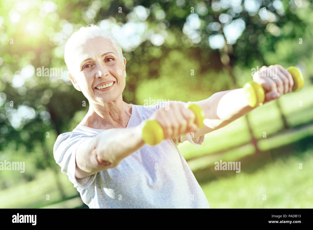Enthusiastic pensioner being satisfied with little hand weights Stock Photo