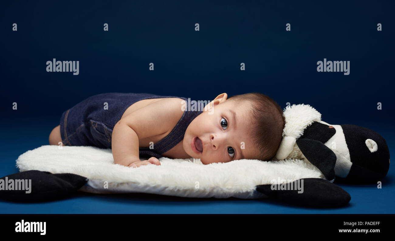 Small Baby With Open Mouth Laying On Pillow In Blue Studio