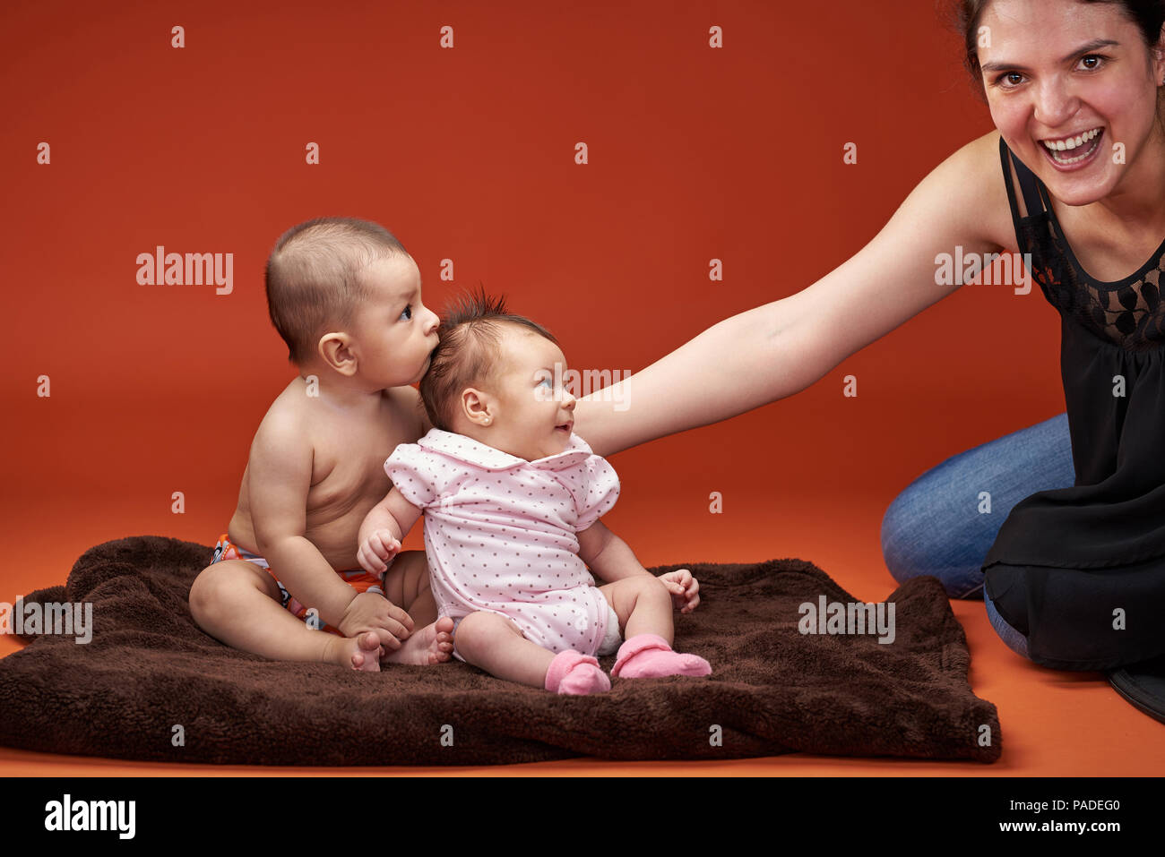 Two small kids look at smiling momin syudio background Stock Photo