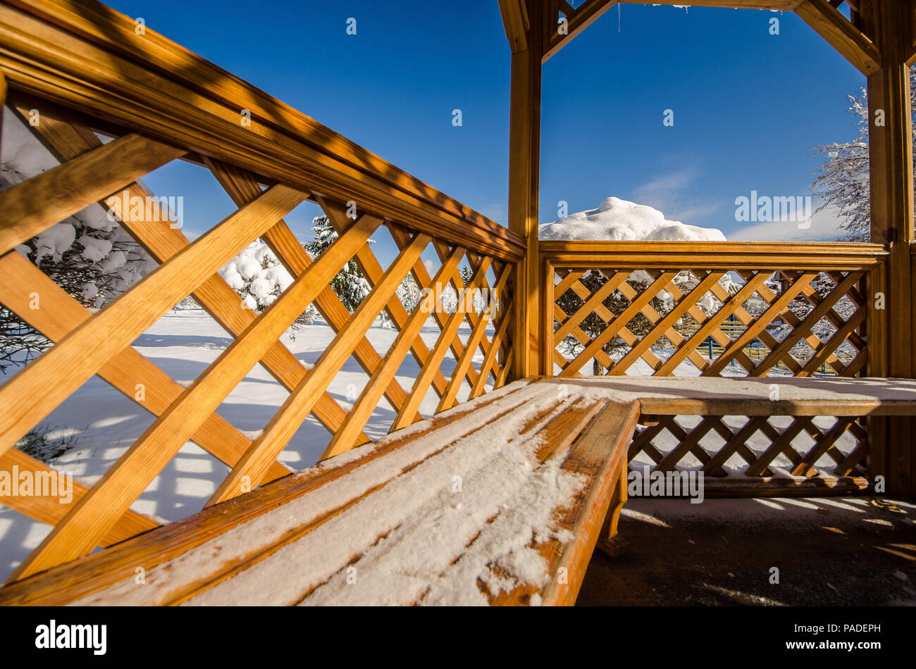 A wooden gazebo in a park in the snow and clear blue sky Stock Photo ...