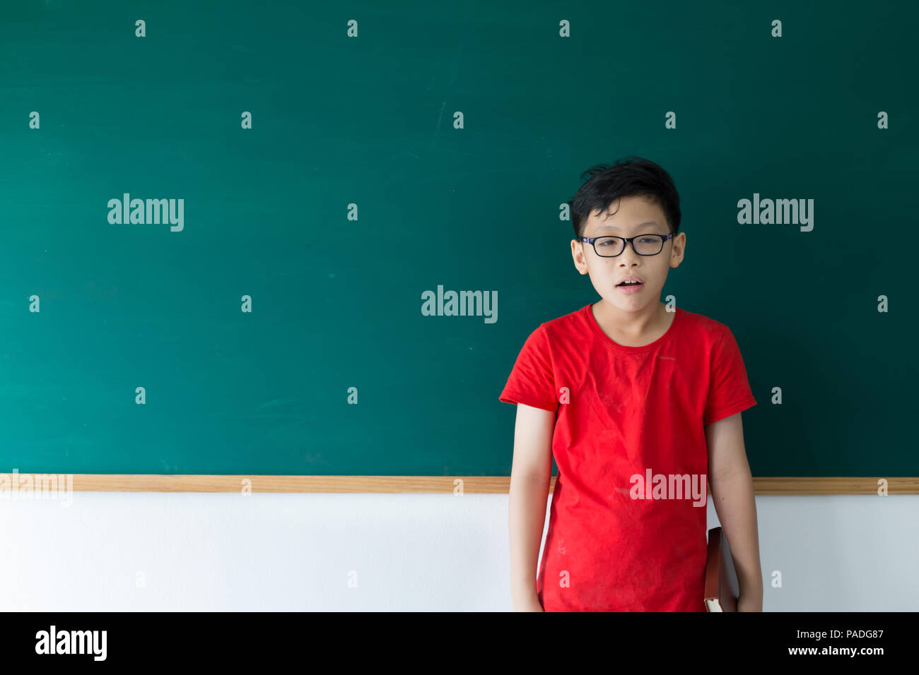 Children boy make nerd face and standingg on chalkboard in classroom at school Stock Photo