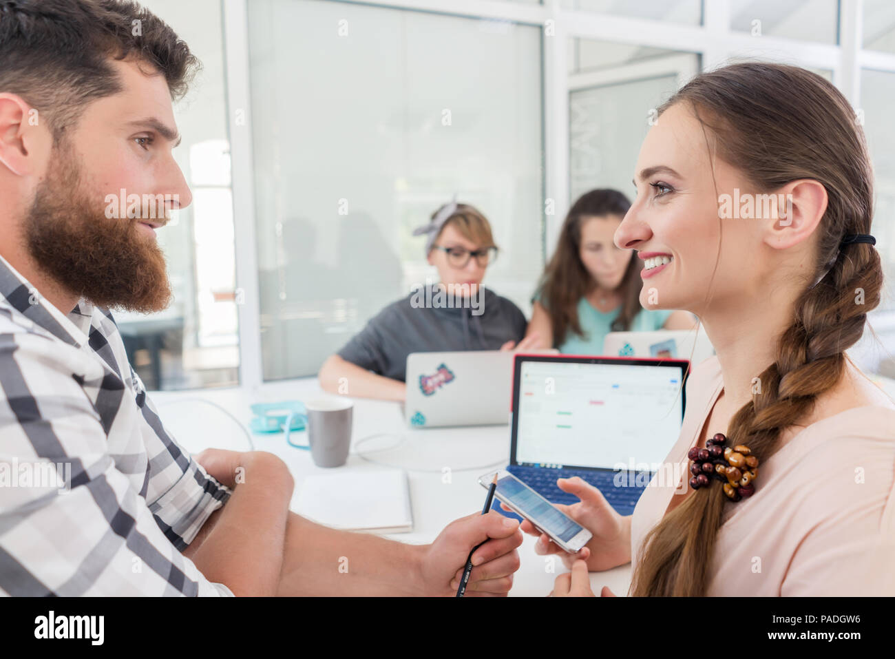 Creative female freelancer smiling to co-worker Stock Photo