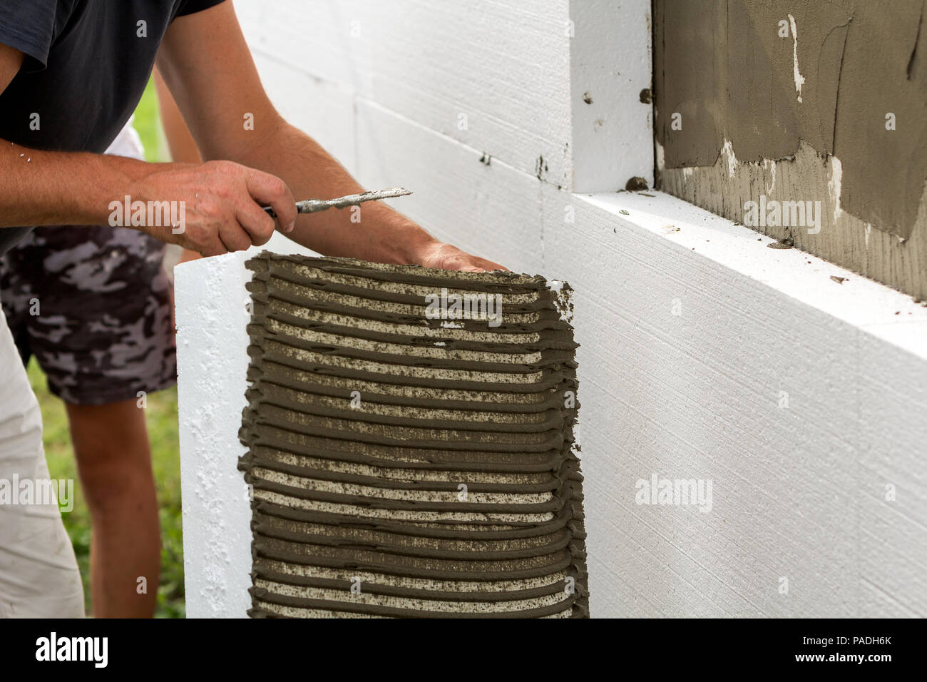 Closeup of detail of worker with trowel gluing white rigid