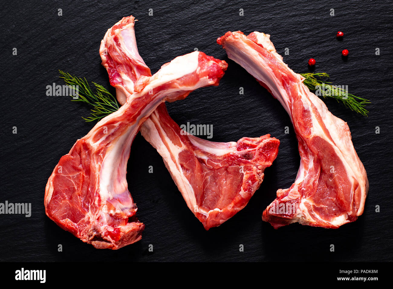 Food concept Organic lamb chops on black slate stone with herbal Stock Photo