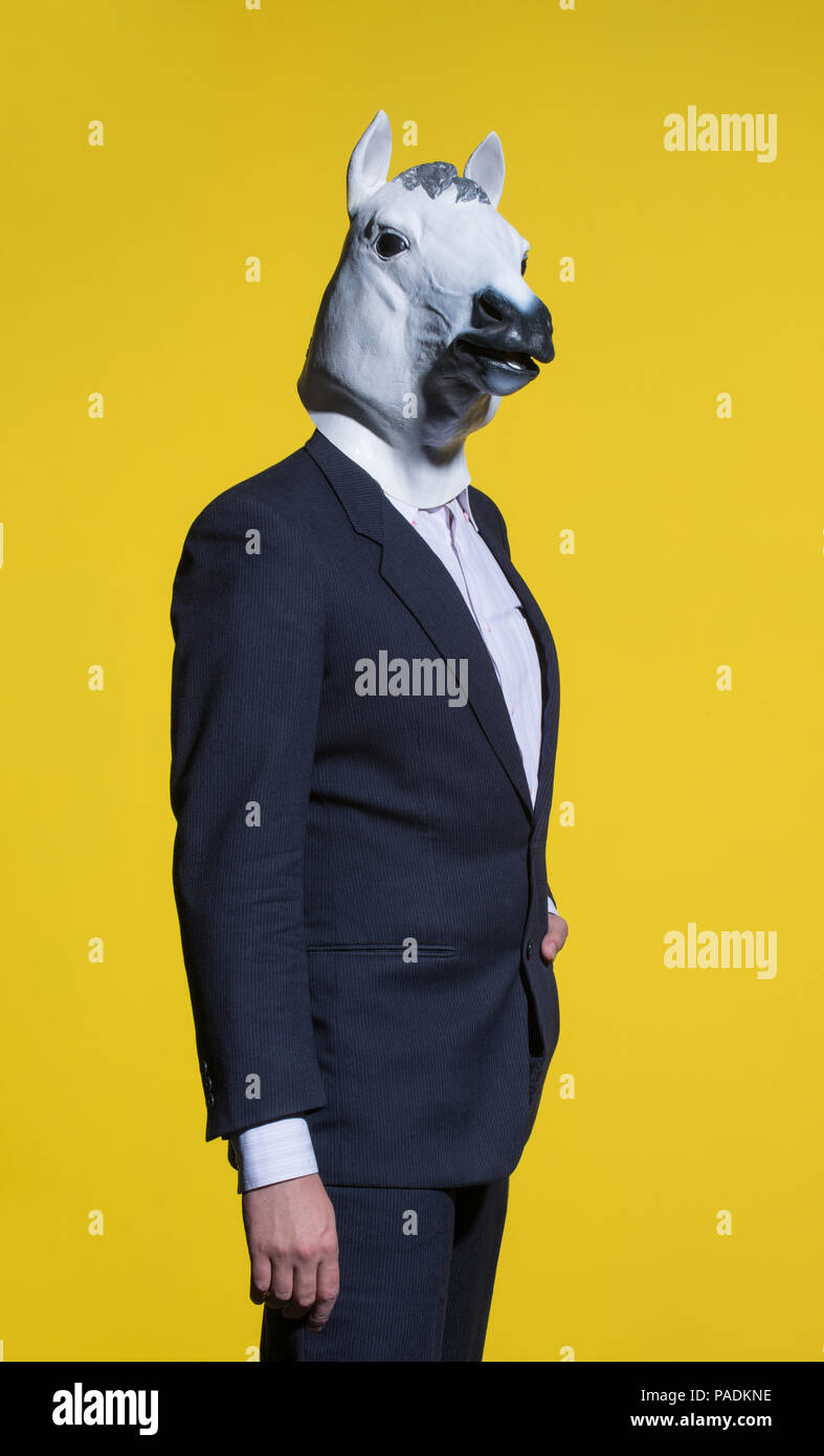 A man in a suit and a horse mask on a yellow background. Conceptual