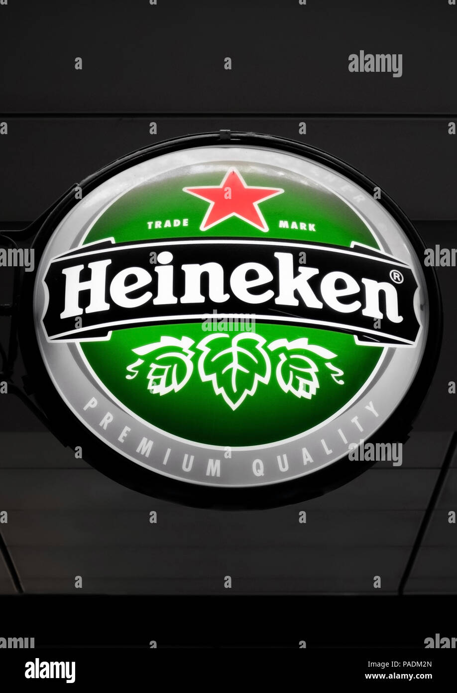 AMSTERDAM, NETHERLANDS - JULY 18, 2018: Round billboard of Heineken lager beer hanging next to pub on dark background. Stock Photo