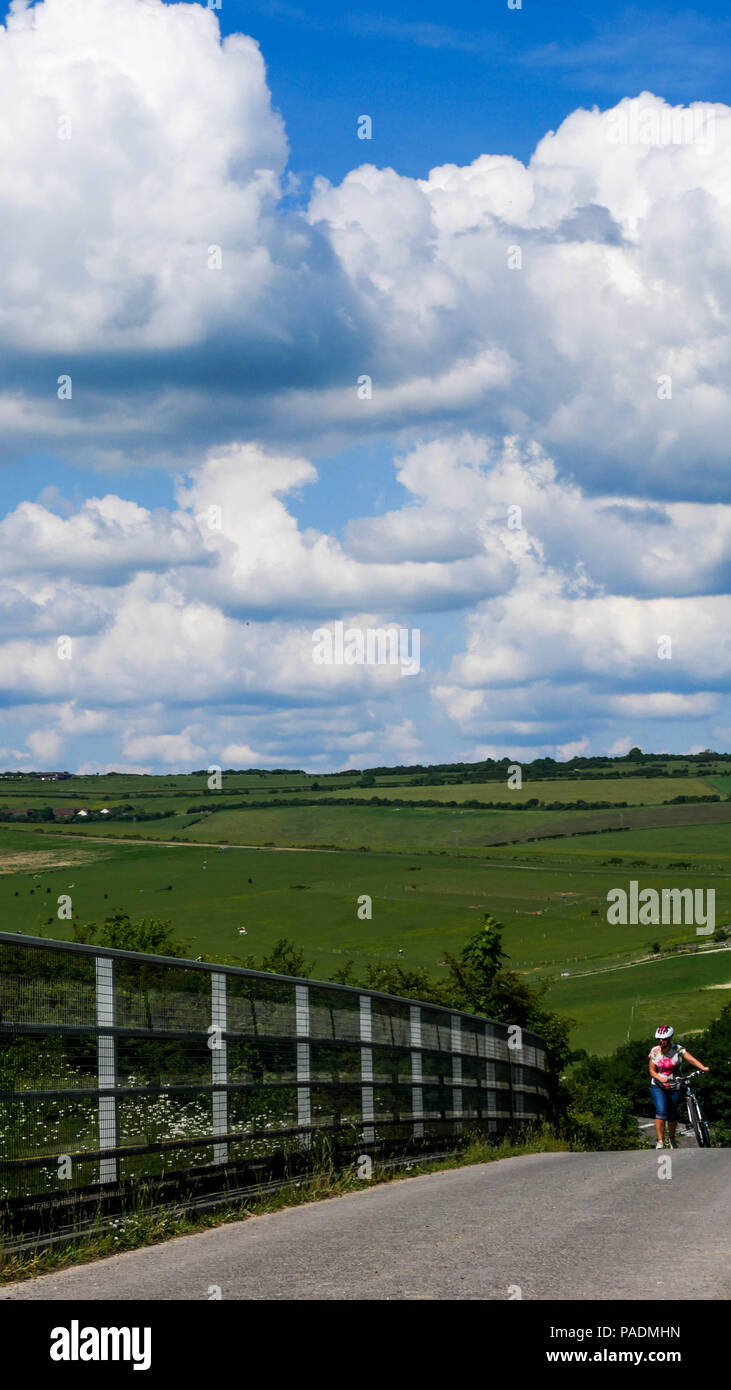 Female cyclist pushing her bicycle over a bridge on the Sussex Downs Stock Photo