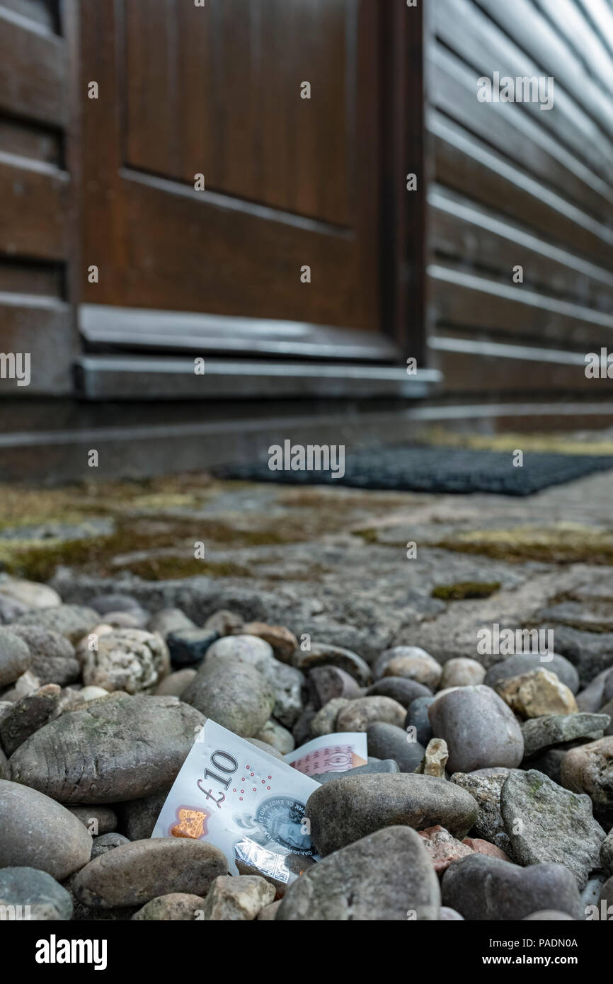 Money  in the form of a bank note on the ground outside a house. Stock Photo