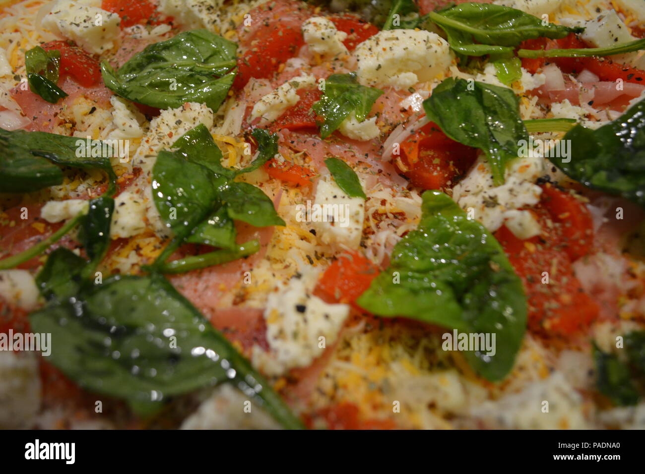 Close Up Texture Background of Pizza Topped with Basil, Mozzarella, Cheese, Red Bell Pepper, Onions, and Garlic Stock Photo
