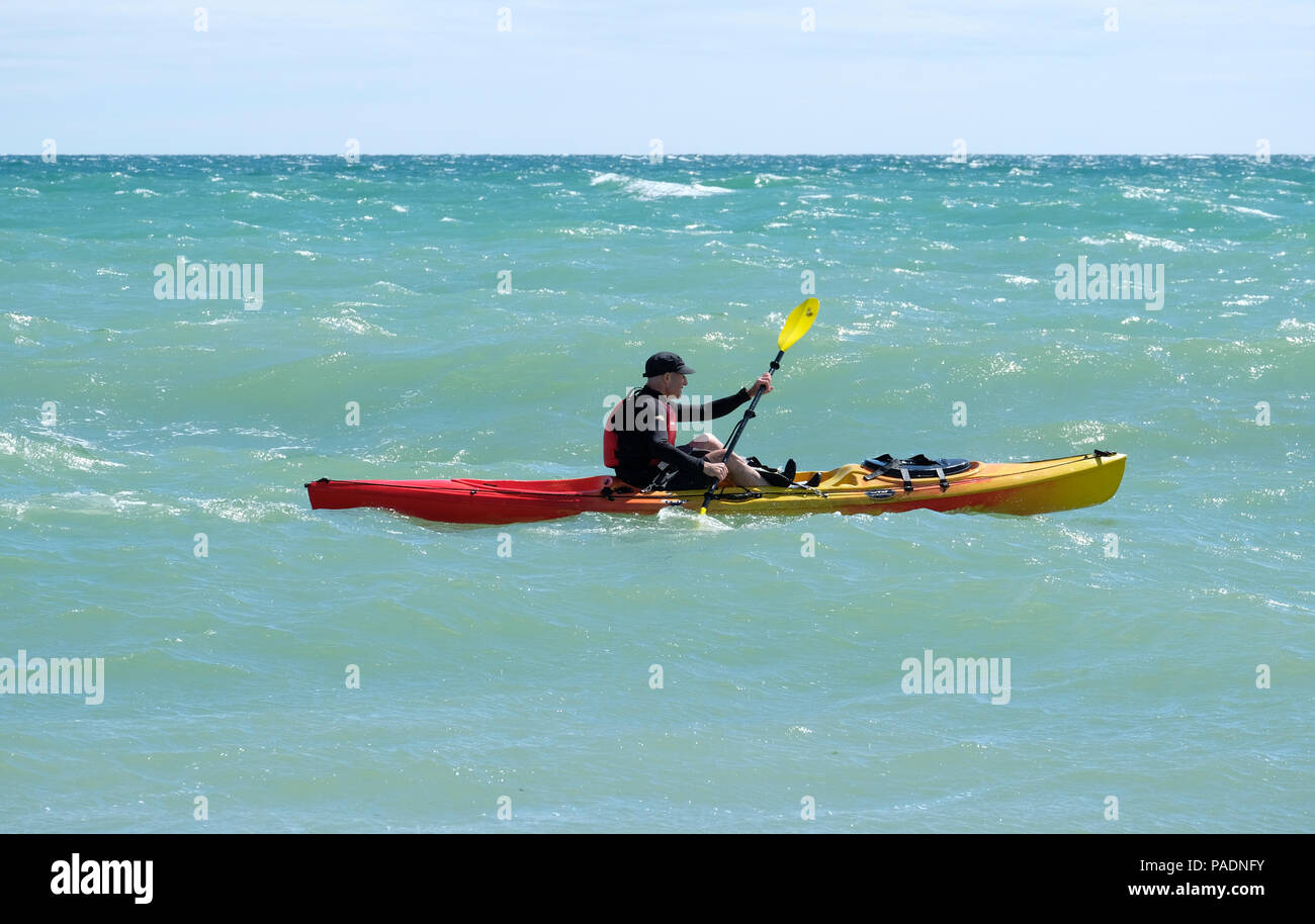 Man wearing life jacket paddling his Kayak in choppy seas off the coast of East Preston, West Sussex, UK. Direction East to West. Stock Photo