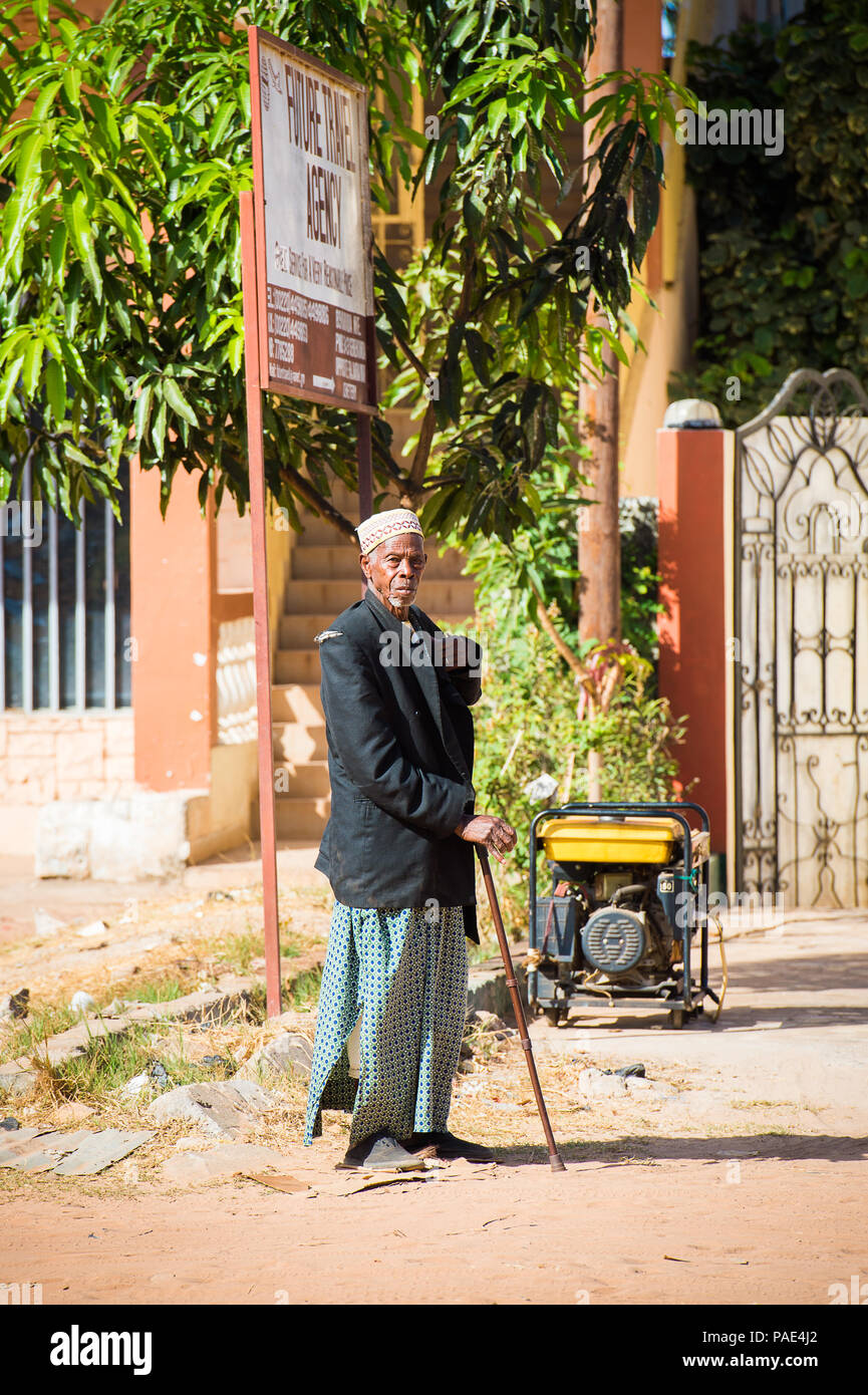 BANJUL, GAMBIA - MAR 14, 2013: Unidentified Gambian old man in long rope and a suit jacket walks with a baston in the street in Gambia, Mar 14, 2013.  Stock Photo