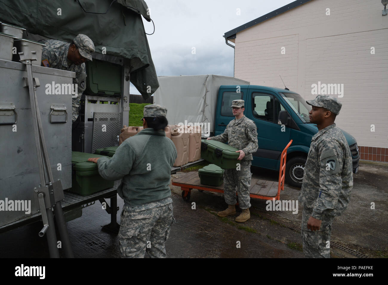 Cooks from the Wiesbaden Strong Teams Cafe Dining Facility (DFAC) brought a Mobile Kitchen Trailer (MKT) out to the Wackernheim Regional Range Facility on 30 March 2016 to feed the U.S. Army Europe Soldiers. The three cooks, (NCO Ssg. Raymond King (under tarp), and Spc. Michelle Santiago-Lopez (center), and Spc. Kallan Clements (right)) and one grill mechanic (Spc. Luke Wilson), set up the MKT, prepared the meals, fed the Soldiers, cleaned the MKT, and broke down the trailer to be used next time. After a long period of not being used, this is the first time the MKT has been set up to be used b Stock Photo