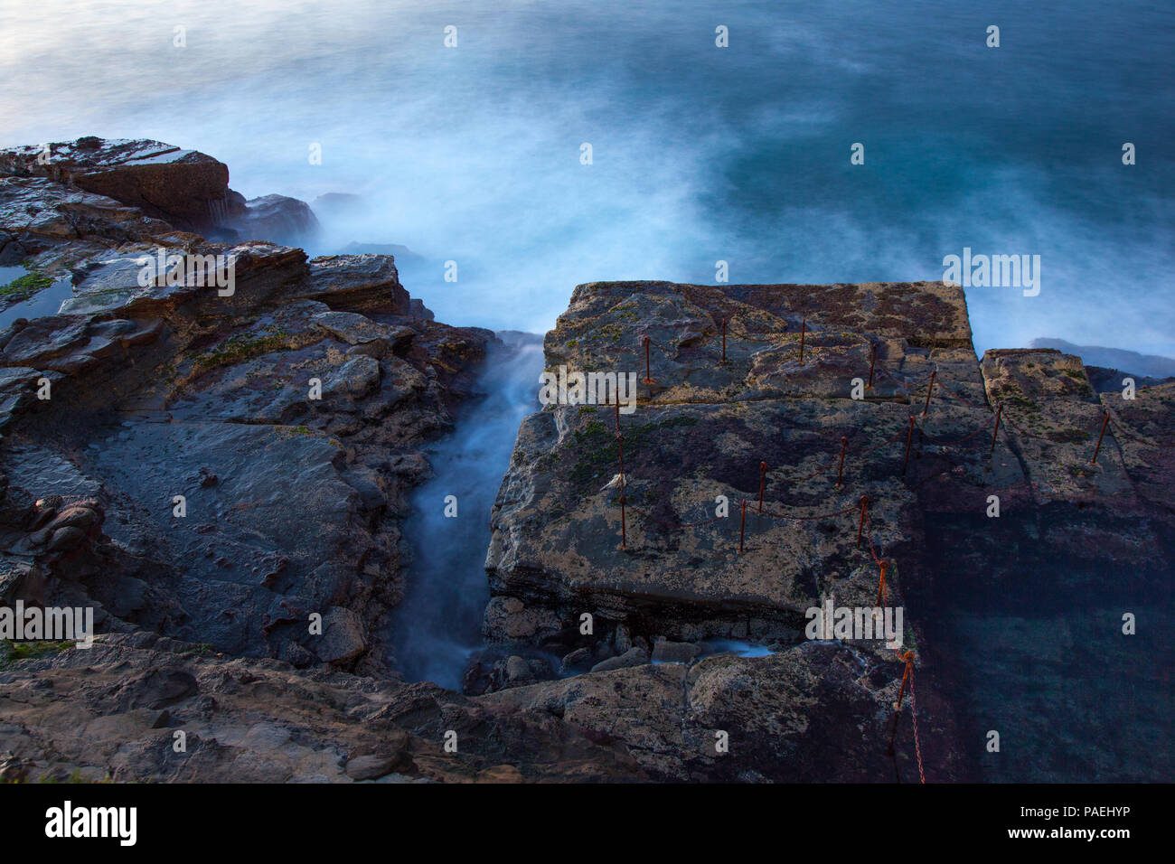 Waves across the rocks at the Bogie Hole Newcastle Australia. This ocean pool was carved from the rocks by convict labour and is a popular landmark in Stock Photo