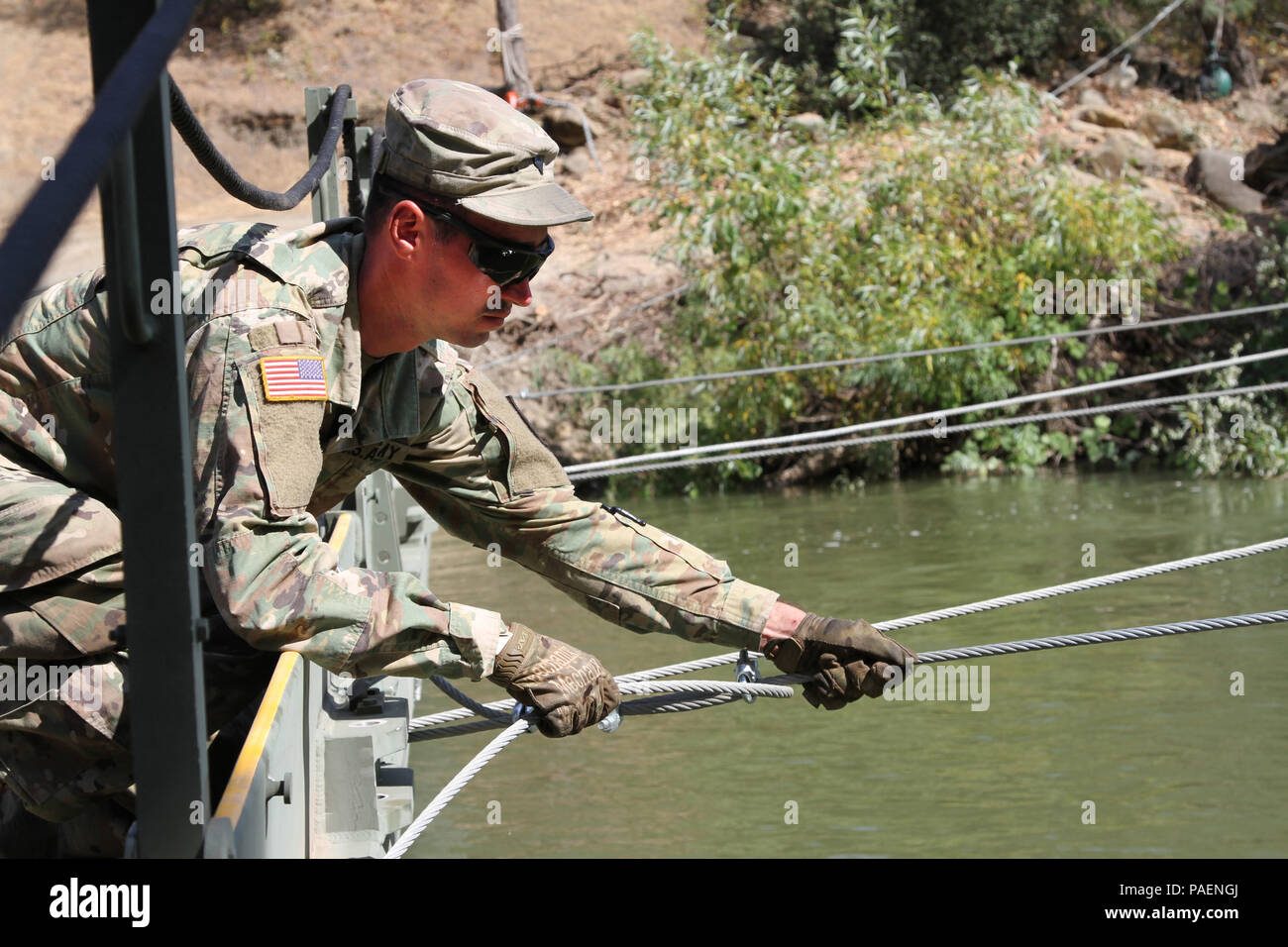U.S. Army Spc. Michael Fereira of the 132nd Multirole Bridge Company, 579th Engineer Battalion, 49th Military Police Brigade, California Army National Guard, checks the tension of a wire cable July 13 at Cache Creek Regional Park, California, where the 132nd constructed a temporary floating bridge to support the California Department of Forestry and Fire Protection (CAL FIRE) efforts to battle Northern California wildfires. This is the second time the CalGuard unit was summoned for a state mission to support CAL FIRE. (U.S. Army National Guard photo by Staff Sgt. Eddie Siguenza) Stock Photo