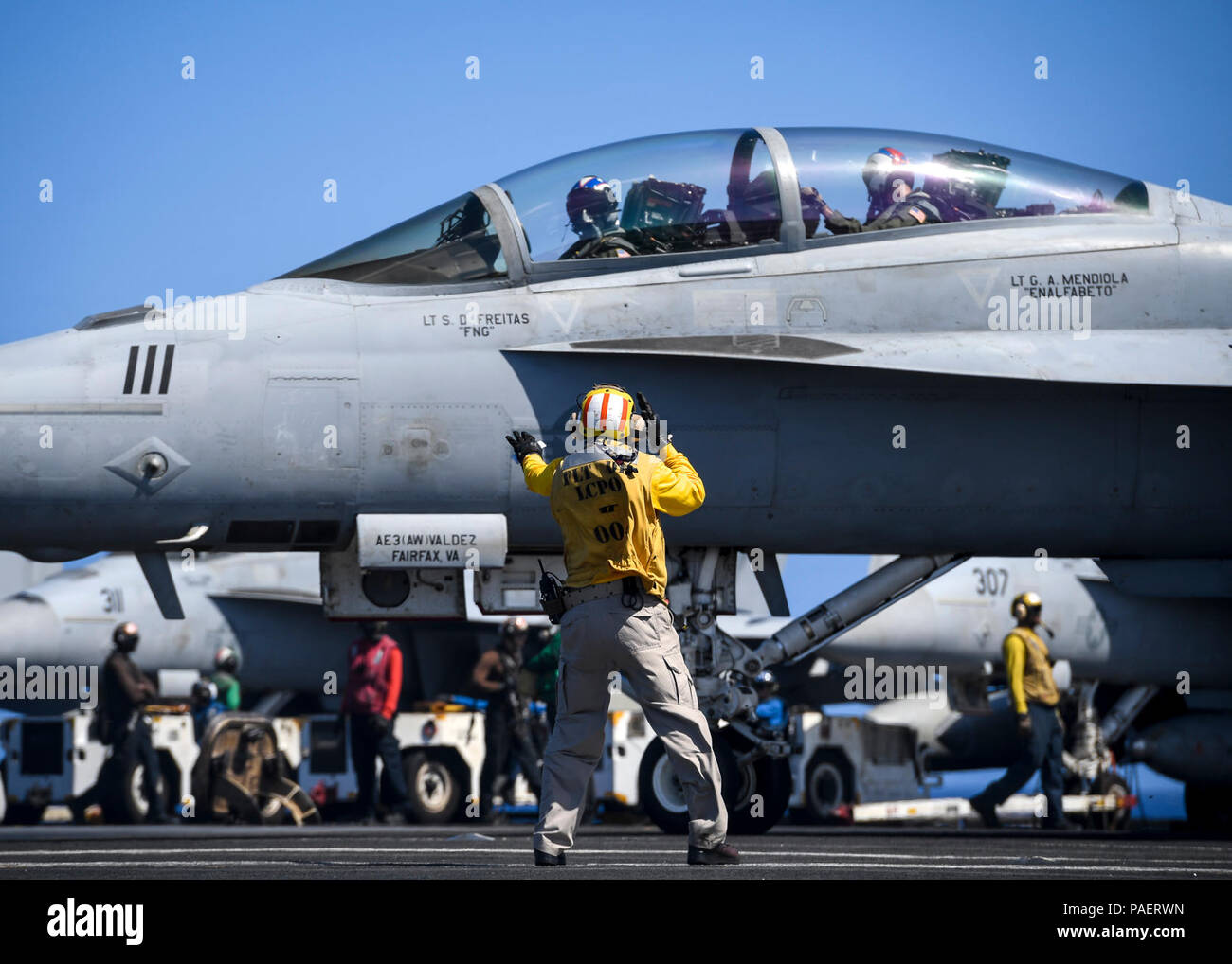 PACIFIC OCEAN (April 19, 2018) Chief Aviation Boatswain’s Mate (Handling) Solomon Thompson signals an F/A-18F Super Hornet assigned to the 'Fighting Redcocks' of Strike Fighter Attack Squadron (VFA) 22 on the flight deck of the aircraft carrier USS Theodore Roosevelt (CVN 71). Theodore Roosevelt is underway for a regularly scheduled deployment in the U.S. 7th Fleet area of operations in support of maritime security operations and theater security cooperation efforts. Stock Photo