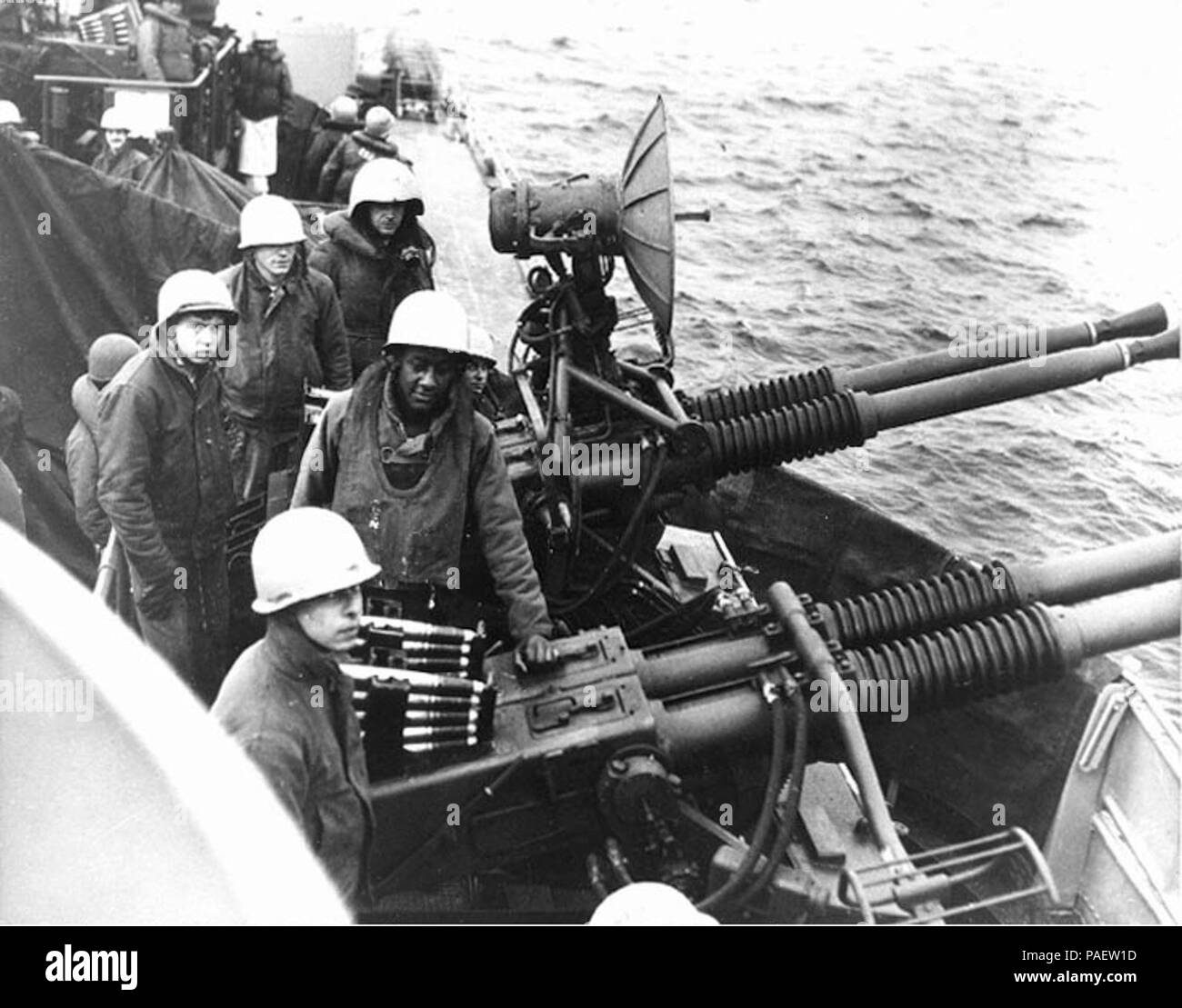 USS English (DD-696): a 40mm gun crew prepares to bombard enemy installations along the Korean coast, circa October 1950 - February 1951. Photograph was received by the Naval Photographic Center on 21 February 1951. Note radar antenna on this quad 40mm mount and ammunition loaded in guns. Another 40mm mount, pointed in the opposite direction, is in the upper left background. Stock Photo