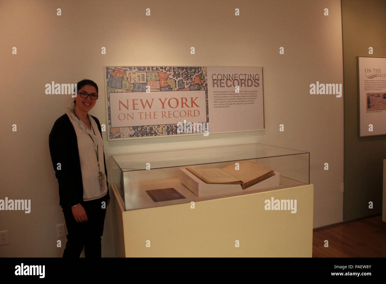 Sara Davis, our Education technican, stands next to the newest exhibit installation in the 'New York on the Record' gallery.  Sara helped curate this exhibit highlighting the 225th anniversary of the U.S. Custom Service with a ledger that documents the earliest transactions in the port of NY, 1789.; Location: National Archives at New York City, New York, New York; Stock Photo