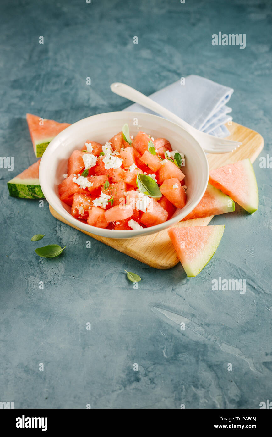 Fresh appetizing summer salad with watermelon cubes, cheese feta and basil in bowl. Served and ready to eat. Clean Detox Weight Loss Concept Stock Photo