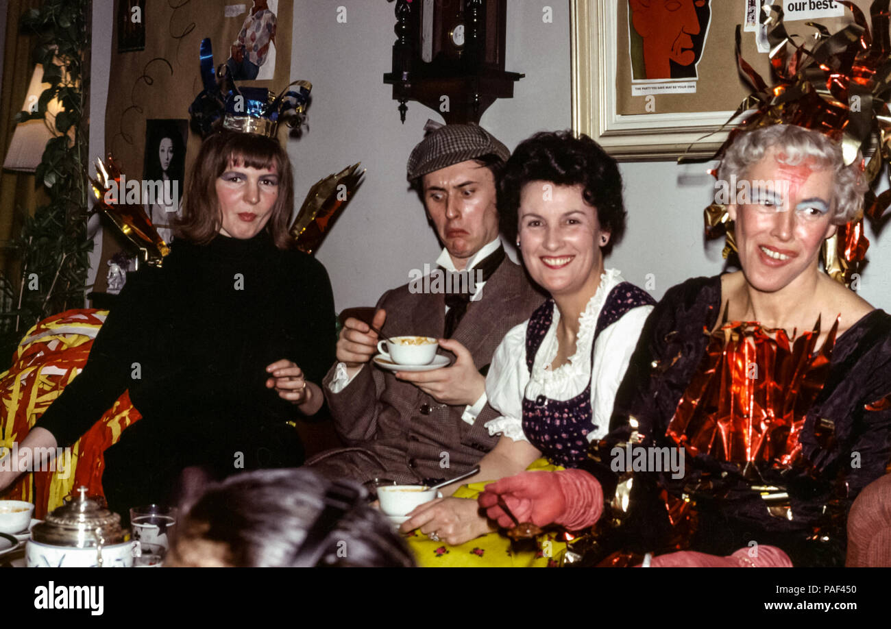 Expats at a fancy dress house party, Hamburg, Germany in the 1960s. Man in fancy dress as Sherlock Holmes wearing a deerstalker hat and women in fancy dress Stock Photo