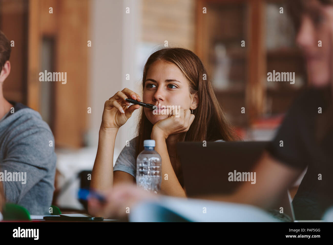 Female student paying attention to lecture in class. Teenage girl studying at the university classroom. Stock Photo