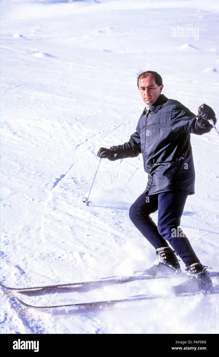 Man skiing down slope with old fashioned leather ski boots and skis in