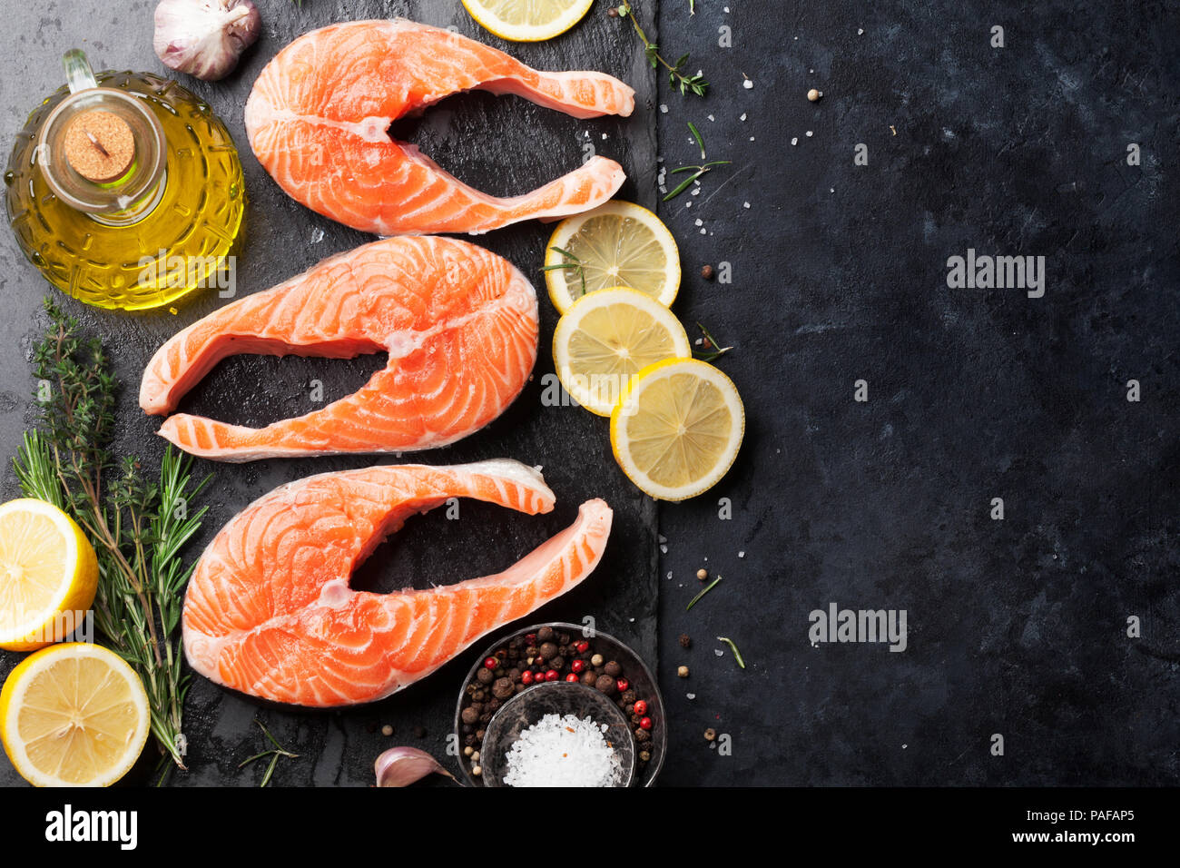 Raw salmon fish steaks with spices cooking on cutting board. Top view ...