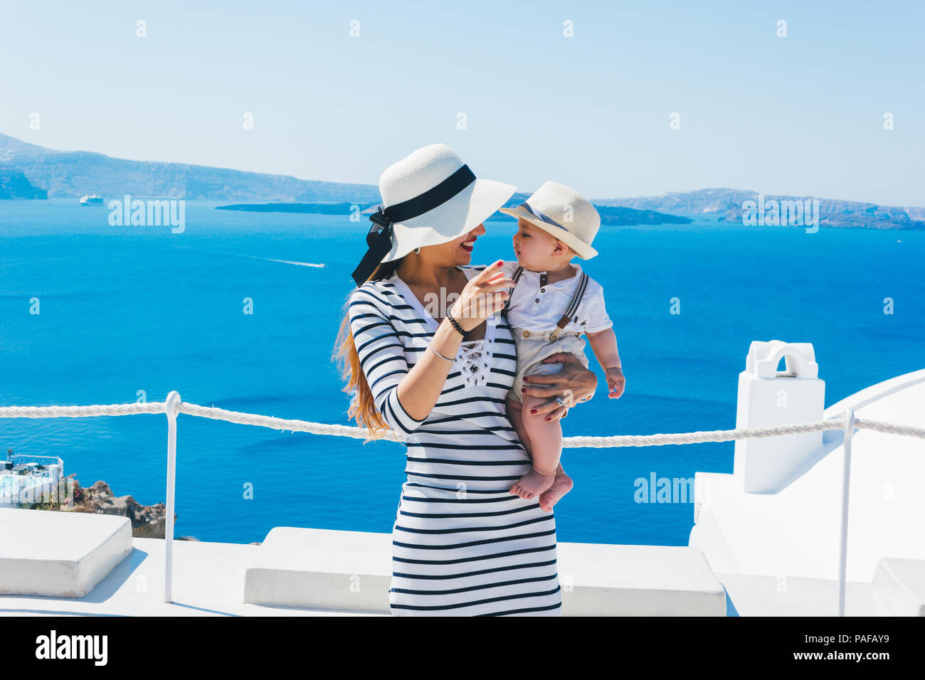 Mother and son enjoying a holiday in Santorini greece, Background the caldera and the famous Santorini volcano Stock Photo