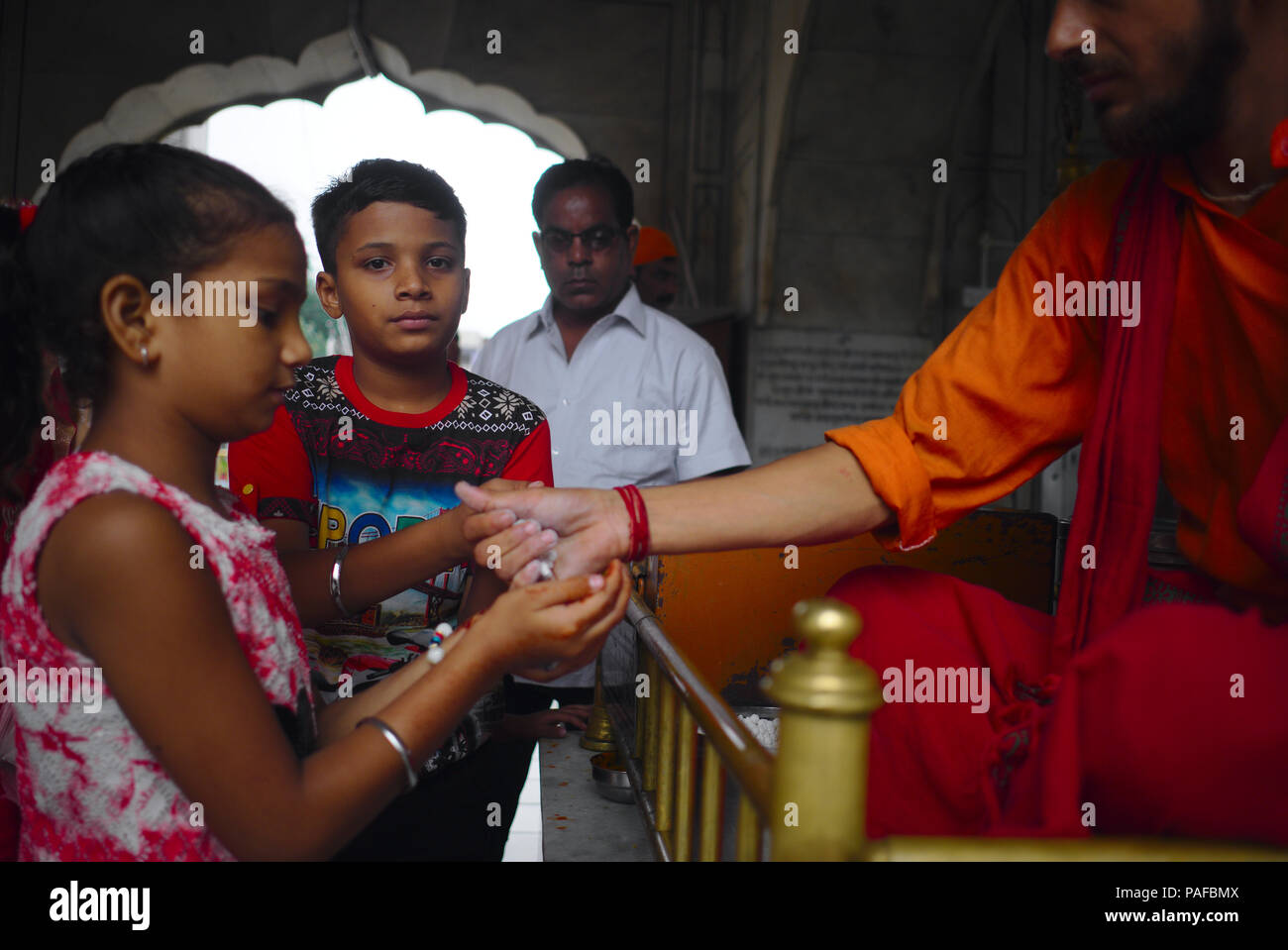 Girl receiving small sweets as blessing at Sitla Mandir temple in Amritsar. Stock Photo